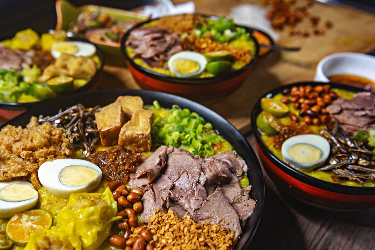 A bowl of traditional Filipino Batchoy with various toppings like boiled egg, crispy garlic, tofu, and beef slices.